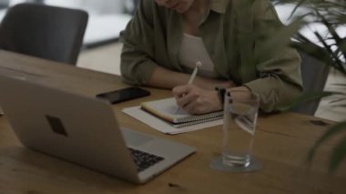 Female fills up the tax form at the table. Bills and pc are in the background