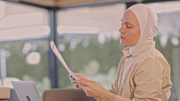 Muzułmanka Czterdziestce Hidżabie Przed Laptopem Analizująca Dokumenty Wysokiej Jakości Materiał — Wideo stockowe