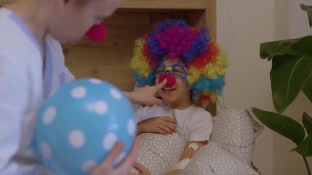 身穿红鼻子专业制服的医学姐姐与病房里的一个男孩玩耍 高质量的4K镜头 — 图库视频影像