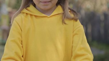 Girl of 7 years dressed in yellow pullover keeps decorated Easter eggs in the palms. High quality 4k footage