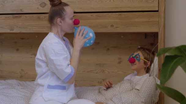 赤い鼻を持つ専門職の制服を着た医療姉妹は 彼の病院病棟の少年と遊ぶ 高品質4K映像 — ストック動画