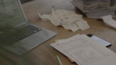 Female fills up the tax form at the table. Bills and pc are in the background