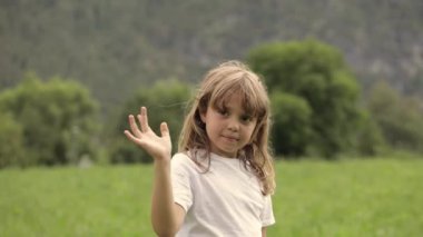 Closeup of a caucasian girl of 7 years old is winking someone in the field. High quality 4k footage