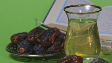 Glass of Turkish tea and dates in a silver plate on a green screen. Vertical shot