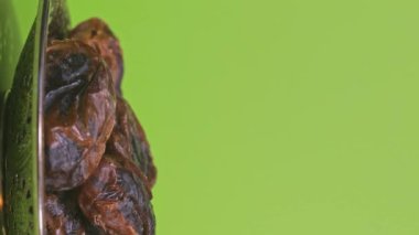 Dates in a silver plate on a green screen. Vertical shot