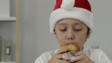 9 yıllık Noel Baba şapkalı çocuk İtalyan Noel tatlı ekmeği yiyor. - Yakın çekim. Yüksek kalite 4k görüntü