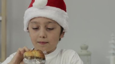9 yıllık Noel Baba şapkalı çocuk İtalyan Noel tatlı ekmeği yiyor. - Yakın çekim. Yüksek kalite 4k görüntü