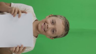 Boy of 9 years holds a sheet of paper. Closeup. High quality footage