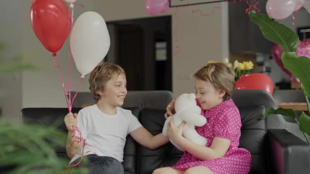 男の子と女の子はバレンタインデーの装飾された部屋のソファに座っています 高品質4K映像 — ストック動画