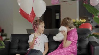 Boy and girl are sitting in the sofa in the decorated room for Valentines Day. High quality 4k footage