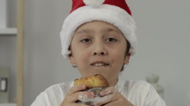 9 yıllık Noel Baba şapkalı çocuk İtalyan Noel tatlı ekmeği yiyor. - Yakın çekim. Yüksek kalite 4k görüntü