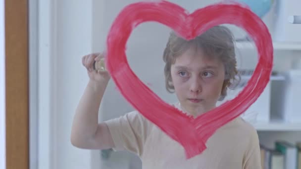 10岁的男孩把红心画在敞开的窗户玻璃上 高质量的4K镜头 — 图库视频影像