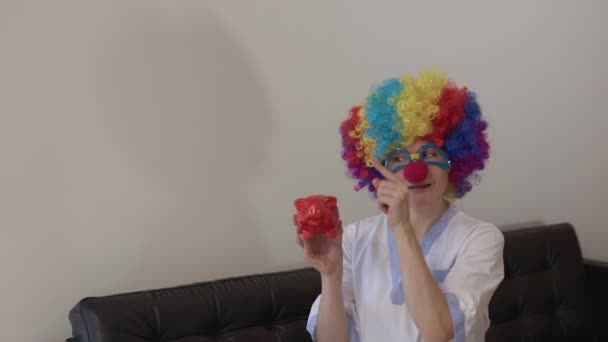 Sorella Medica Parrucca Clown Naso Rosso Occhiali Mostra Salvadanaio Rosso — Video Stock