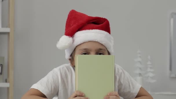Niño Años Santas Sombrero Esconde Detrás Del Libro Primer Plano — Vídeo de stock