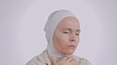 35-40 yaşları arasında, başörtüsü takmış genç Müslüman kadın öksürüyor.