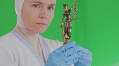Themis heykeli olan tıbbi giysili Müslüman bir kadın. Yüksek kalite 4k görüntü