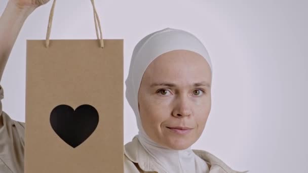 Söt Muslimsk Hona Visar Kraftpapperspåse Med Hjärtfönster Högkvalitativ Film — Stockvideo