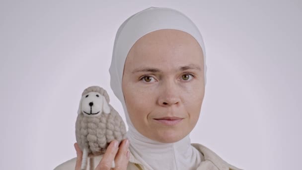 ヒジャブの魅力的なイスラム教徒の女性は おもちゃの羊を飼っています 高品質の4K映像 — ストック動画