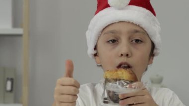 9 yıllık Noel Baba şapkalı çocuk İtalyan Noel tatlı ekmeği yiyor. - Yakın çekim. Yüksek kalite 4k görüntü