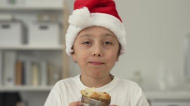 9 yıllık Noel Baba şapkalı çocuk İtalyan Noel tatlı ekmeği yiyor. - Yakın çekim. Yüksek kalite 4k görüntü