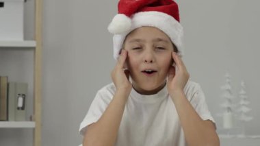 9 yıllık Noel Baba şapkalı çocuk gözlerini açtı. - Yakın çekim. Yüksek kalite 4k görüntü