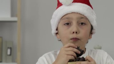 9 yıllık Noel Baba şapkalı çocuk zencefilli ekmek yiyor. - Yakın çekim. Yüksek kalite 4k görüntü