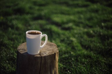Bahçedeki ahşap bir masada bir fincan kahve duruyor.