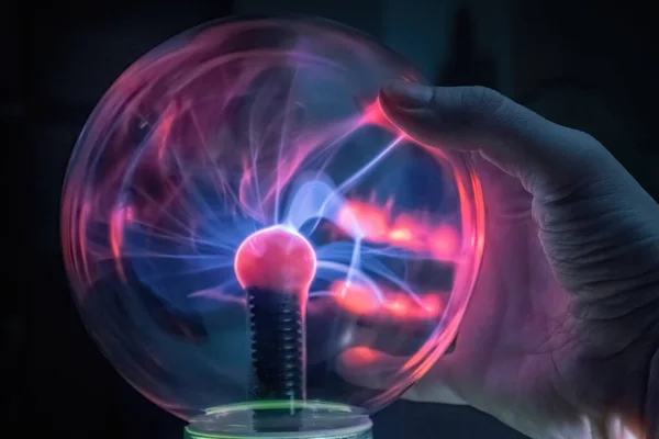Scientist hand is touching a plasma ball.