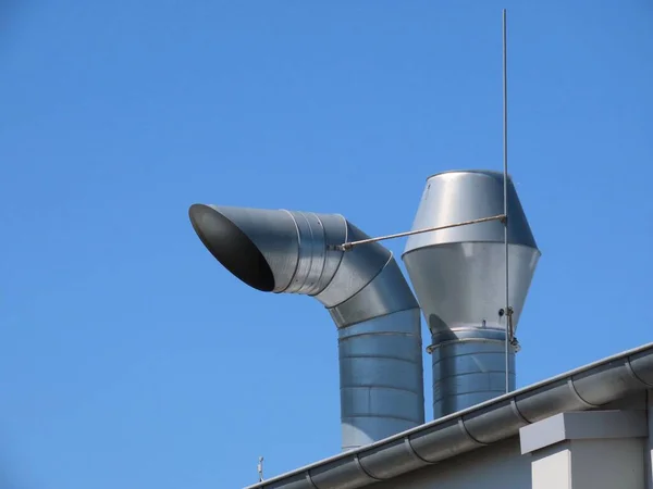 Fresh air intake - exhaust chimneys of a ventilation system on top of a roof against bright blue sky