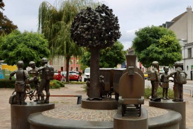 Group of bronze statues of passengers and train next to train station. Diekirch, Luxembourg - September 19, 2022