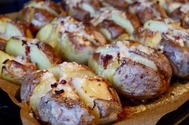 Potatoes cross cut, baked with peel or jacket on, toped with bacon lardons and cheese