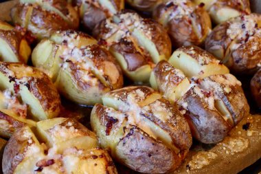 Potatoes cross cut, baked with peel or jacket on, toped with bacon lardons and cheese