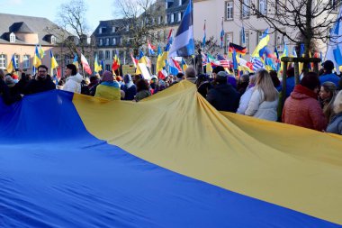 Rally in support of Ukraine on one year anniversary since the invasion. Big Ukrainian flag in foreground. Luxembourg, Luxembourg - February 25, 2023