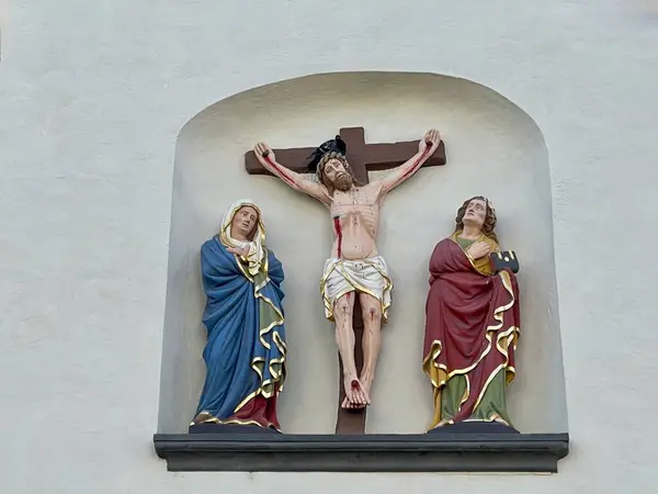 トリアーのセントギャングルフ教会の正面に中世の十字架 十字架上のイエスと喪に服する母マリアと聖ヨハネ ストックフォト