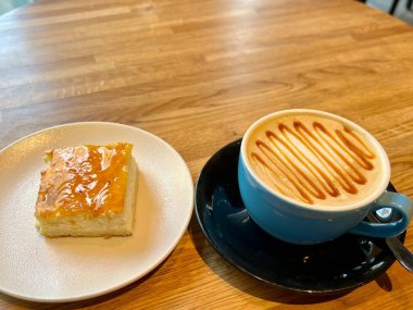 Riga, Letonya 'da bir kafede karamel süslemeli Teal fincan kahve ve kare bir cheesecake.