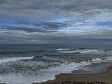 Bay of Biscay at Biarritz, Milady beach, big waves on sand, clouds in sky, there is a storm coming clipart