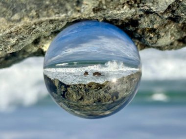 Cristal ball reflecting a seascape Bay of Biscay at Biarritz, Milady beach. Waves splashing over rocks clipart