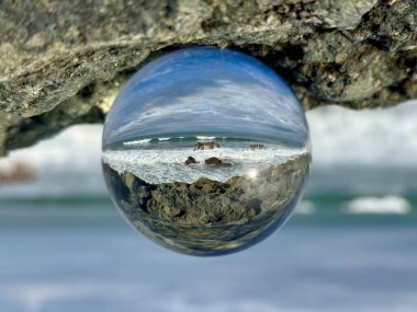 Cristal ball reflecting a seascape Bay of Biscay at Biarritz, Milady beach. Waves splashing over rocks clipart