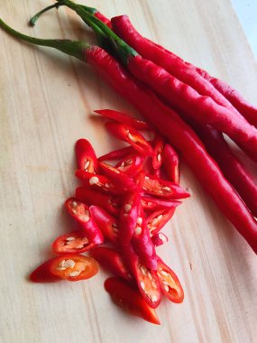 Açık ahşap bir tahtada sergilenen canlı, yakın plan kırmızı biberler renklerine ve dokusuna vurgu yapıyor. Baharatlı yemek kavramları için mükemmel..