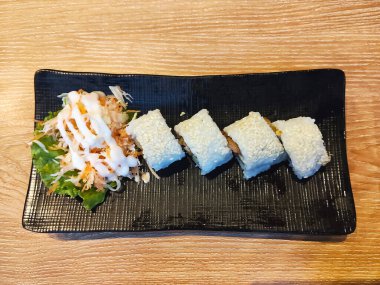 Susam tohumlu taze bir tabak suşi, yanında kremalı mayonez soslu salata..