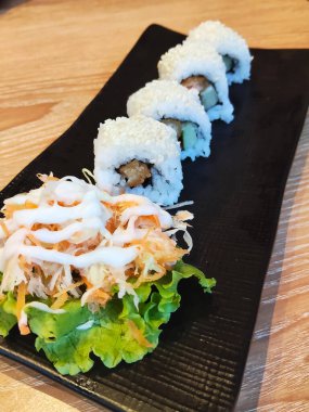 Susam tohumlu taze bir tabak suşi, yanında kremalı mayonez soslu bir salata..