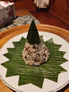 Nasi Tutug Oncom 'un yakın çekimi, geleneksel bir Endonezya yemeği karışık pirinç ve mayalanmış oncom, muz yaprağı üzerinde güzel bir koni şeklinde sunulur..