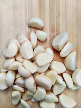 Canlı, taze sarımsak soğanları ve ahşap bir tahtanın üzerinde bir yığın temiz karanfil. Yemek blogları ve sağlıklı yaşam temaları için mükemmel..