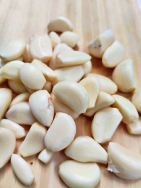 Canlı, taze sarımsak soğanları ve ahşap bir tahtanın üzerinde bir yığın temiz karanfil. Yemek blogları ve sağlıklı yaşam temaları için mükemmel..