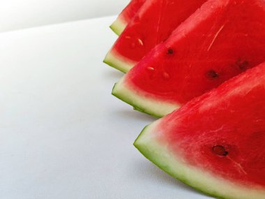 Taze, sulu karpuz dilimi ve arka planda koca bir karpuz. Sağlıklı bir yaz yemeği için mükemmel..