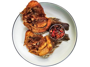 İki kızartılmış tilapia balığının yakın çekimi beyaz bir tabakta, yanında baharatlı biber sambal, popüler ve lezzetli bir Asya yemeği..