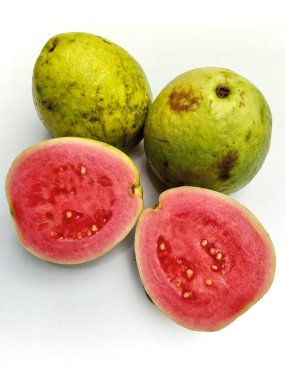 Taze, olgun pembe guava meyvesi, bütün ve ikiye bölünmüş, tatlı, sulu etini ve tohumlarını temiz, beyaz bir arka planda sergiliyor..