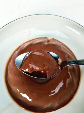 Açık mavi bir kasede servis edilen parlak bir yüzeyi olan pürüzsüz ve dejenere olmuş çikolatalı ipeksi bir puding. Bu basit ve lezzetli bir tatlı..