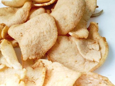 Kıtır Endonezya karides krakerleri, ya da kerupuk udang, beyaz arka planı temiz, tahta bir tahtanın üzerinde bulunan klasik bir gevrek atıştırmalık ya da yan yemektir..