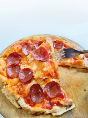 Eritilmiş mozzarella peynirli ve altın hamurlu bir pepperonili pizza kırsal ahşap servis tahtasının üzerinde sunuluyor..